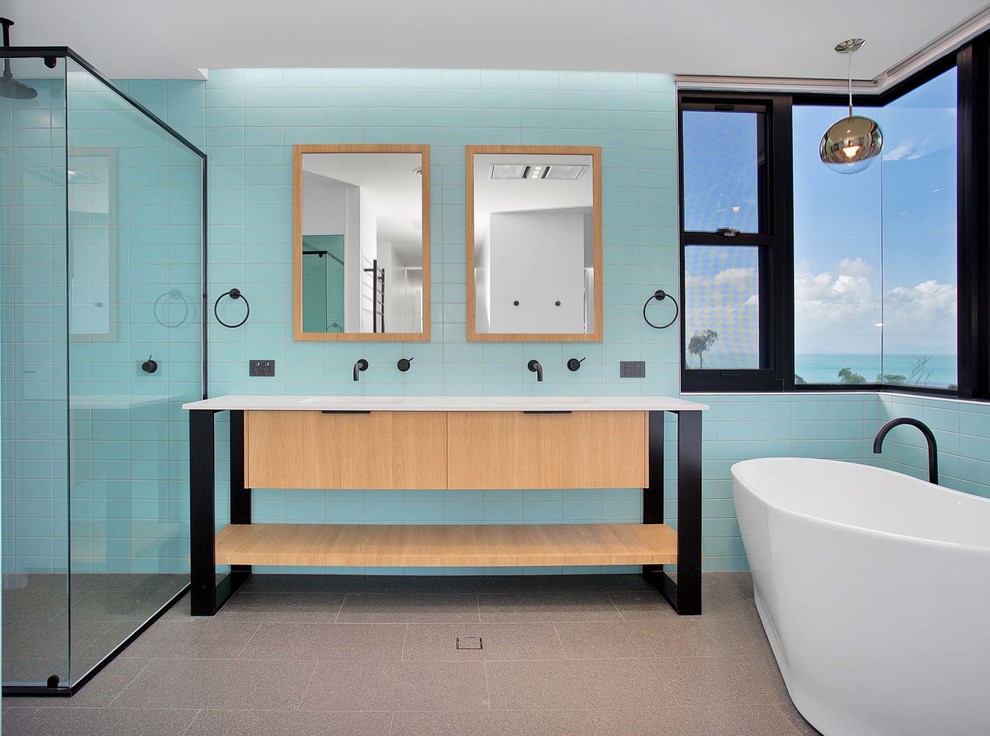 Photo of a contemporary master bathroom in Other with flat-panel cabinets, light wood cabinets, a freestanding tub, a curbless shower, blue tile, green tile, subway tile, blue walls, an integrated sink, grey floor and white benchtops.