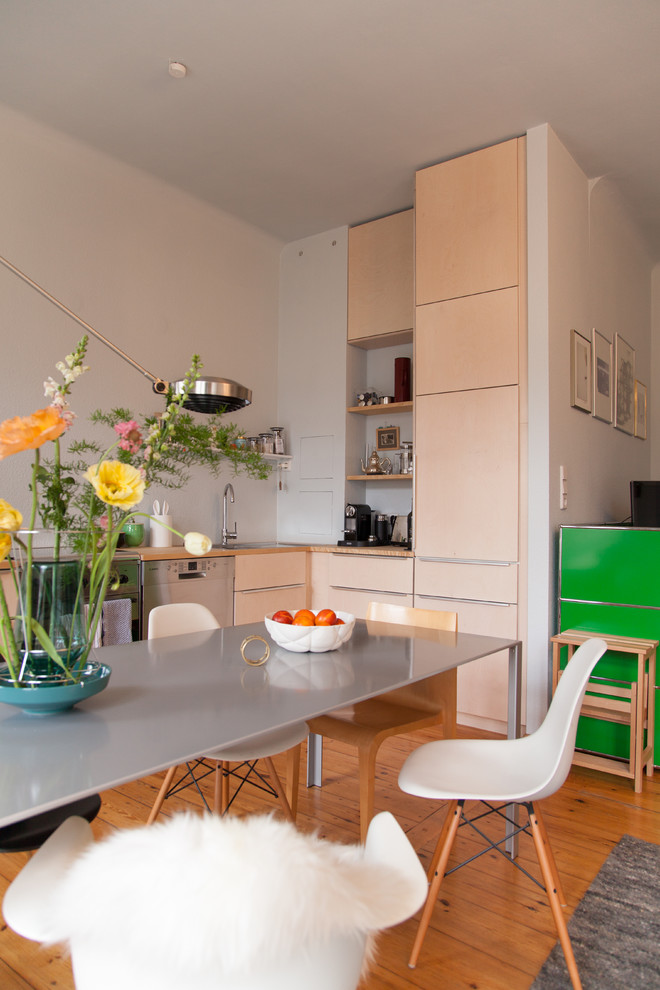 Mittelgroße Skandinavische Wohnküche ohne Insel in L-Form mit flächenbündigen Schrankfronten, beigen Schränken, Arbeitsplatte aus Holz, Küchenrückwand in Blau, Einbauwaschbecken, Küchengeräten aus Edelstahl, hellem Holzboden und braunem Boden in Berlin