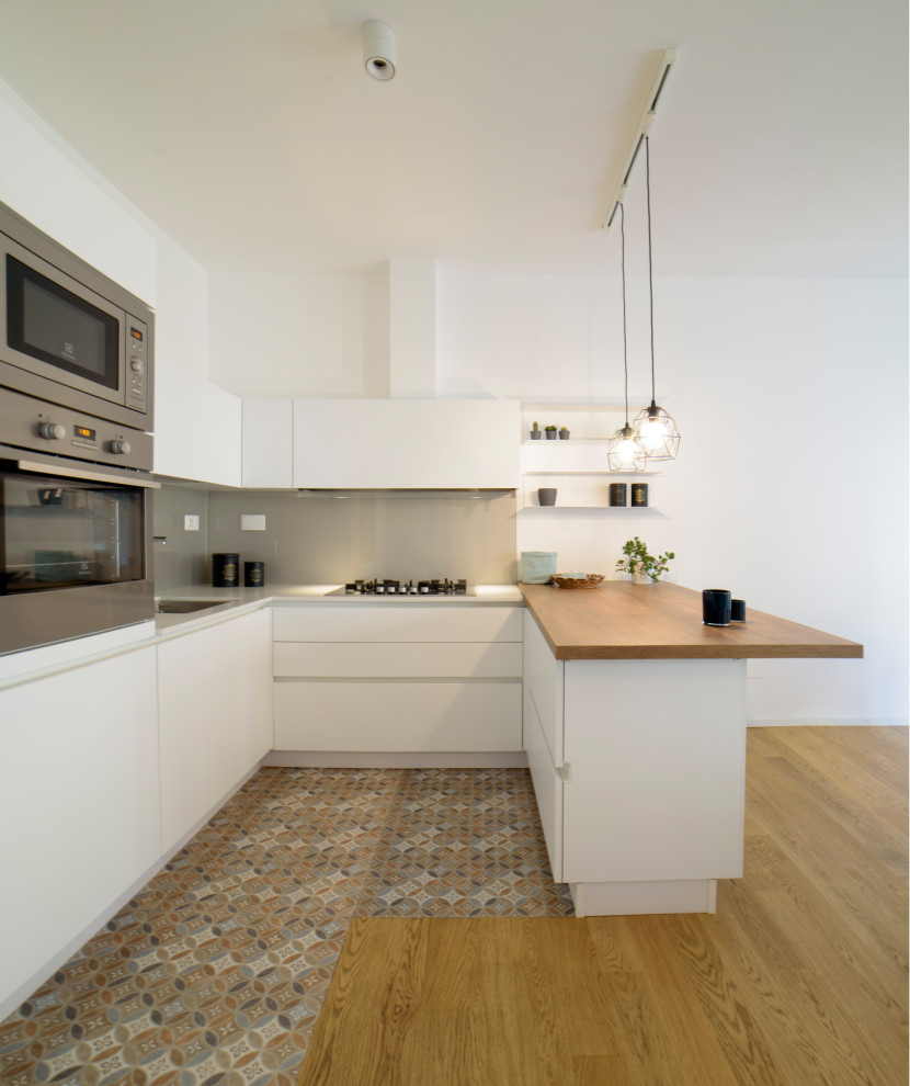 Inspiration for a large modern u-shaped open plan kitchen in Rome with an undermount sink, flat-panel cabinets, white cabinets, quartz benchtops, grey splashback, glass sheet splashback, stainless steel appliances, porcelain floors, a peninsula, multi-coloured floor and grey benchtop.