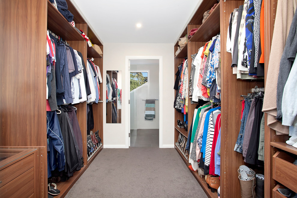 Expansive gender-neutral walk-in wardrobe in Sydney with open cabinets, medium wood cabinets and carpet.