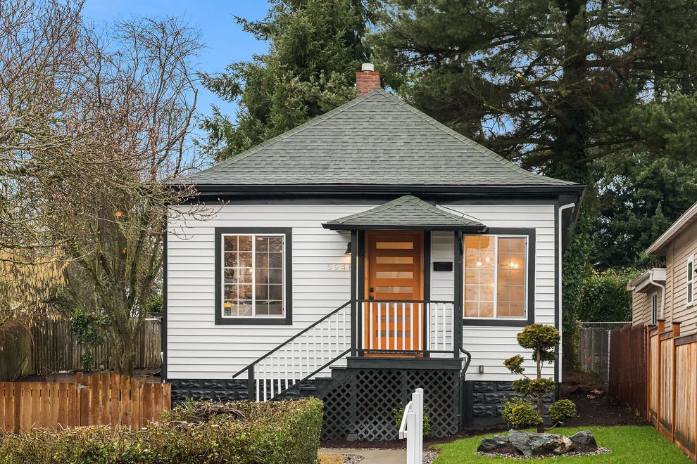 This is an example of a transitional one-storey white house exterior in Seattle with vinyl siding, a gable roof and a shingle roof.