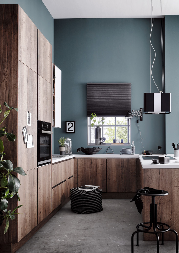 Design ideas for a small industrial u-shaped eat-in kitchen in Dresden with a drop-in sink, flat-panel cabinets, brown cabinets, wood benchtops, blue splashback, brick splashback, dark hardwood floors, a peninsula, brown floor and black appliances.