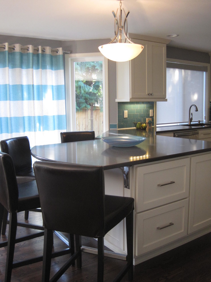 Example of a mid-sized transitional u-shaped dark wood floor home design design in Seattle with an undermount sink, shaker cabinets, white cabinets, quartz countertops, blue backsplash, glass tile backsplash, stainless steel appliances and a peninsula