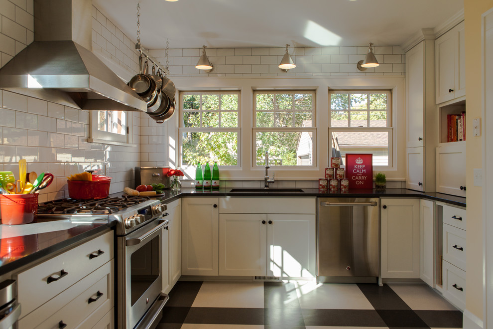 Photo of a transitional separate kitchen in Minneapolis with stainless steel appliances, an undermount sink, recessed-panel cabinets, white cabinets, white splashback, subway tile splashback and multi-coloured floor.