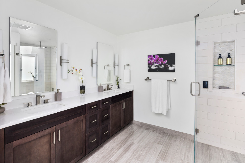 Photo of a large transitional master bathroom in Seattle with shaker cabinets, dark wood cabinets, white tile, light hardwood floors, an undermount sink, engineered quartz benchtops, a hinged shower door, white benchtops, a niche, a double vanity and a built-in vanity.