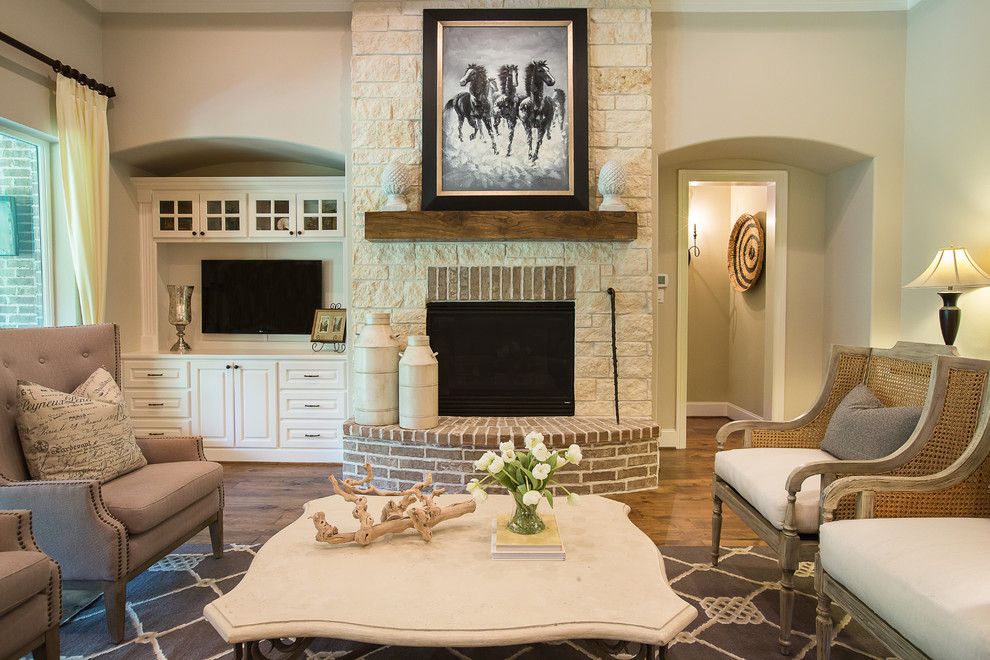 Inspiration for a traditional family room in Dallas with beige walls, a standard fireplace, a wall-mounted tv, medium hardwood floors and a stone fireplace surround.