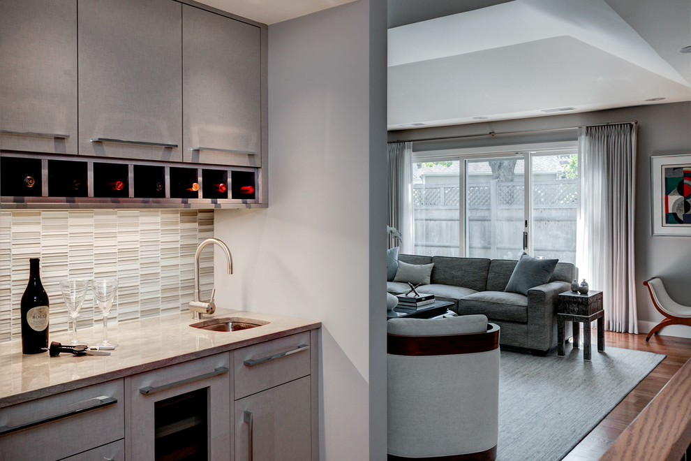 This is an example of a small transitional single-wall wet bar in Boston with an undermount sink, flat-panel cabinets, beige cabinets, limestone benchtops, beige splashback and mosaic tile splashback.