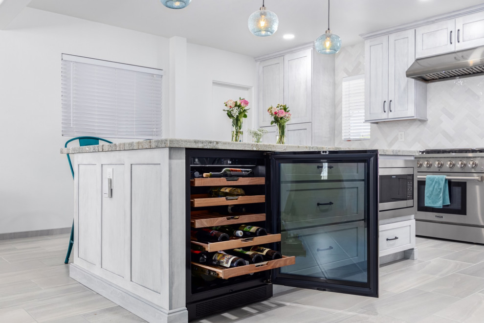 Example of a transitional l-shaped kitchen design in Phoenix with a single-bowl sink, shaker cabinets, white cabinets, granite countertops, white backsplash and stainless steel appliances