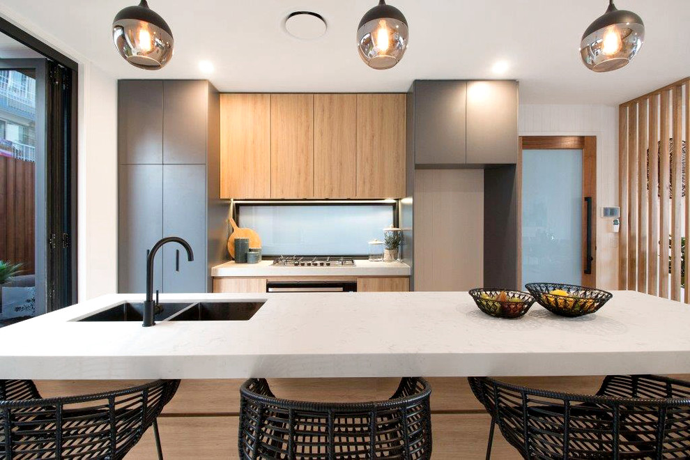 Design ideas for a mid-sized contemporary galley eat-in kitchen in Gold Coast - Tweed with an undermount sink, flat-panel cabinets, grey cabinets, quartz benchtops, blue splashback, black appliances, with island, white benchtop and light hardwood floors.