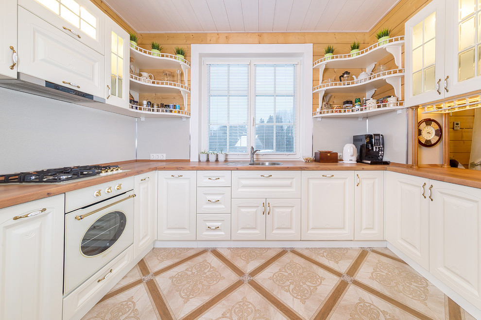 This is an example of a small transitional u-shaped eat-in kitchen in Saint Petersburg with a drop-in sink, recessed-panel cabinets, white cabinets, wood benchtops and no island.