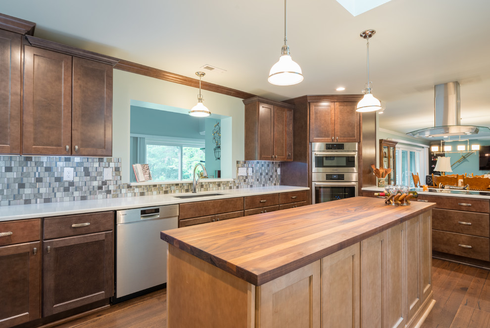 Mid-sized dark wood floor eat-in kitchen photo with shaker cabinets, brown cabinets, glass tile backsplash, stainless steel appliances and an island