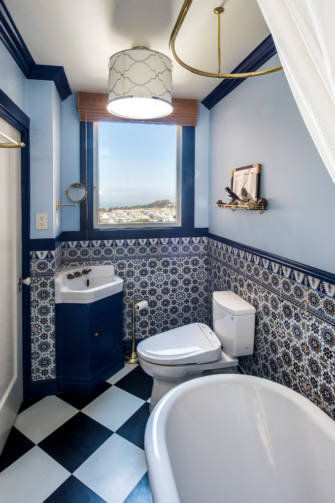 This is an example of a large traditional 3/4 bathroom in San Francisco with a claw-foot tub, blue walls, shaker cabinets, blue cabinets, a two-piece toilet, blue tile, multi-coloured tile, ceramic tile, a drop-in sink, white benchtops, vinyl floors and multi-coloured floor.
