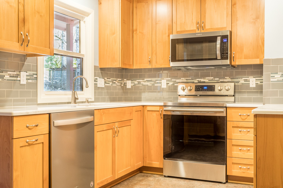 Example of a mid-sized transitional u-shaped vinyl floor and brown floor enclosed kitchen design with an undermount sink, shaker cabinets, gray cabinets, quartz countertops, gray backsplash, subway tile backsplash, stainless steel appliances, no island and white countertops
