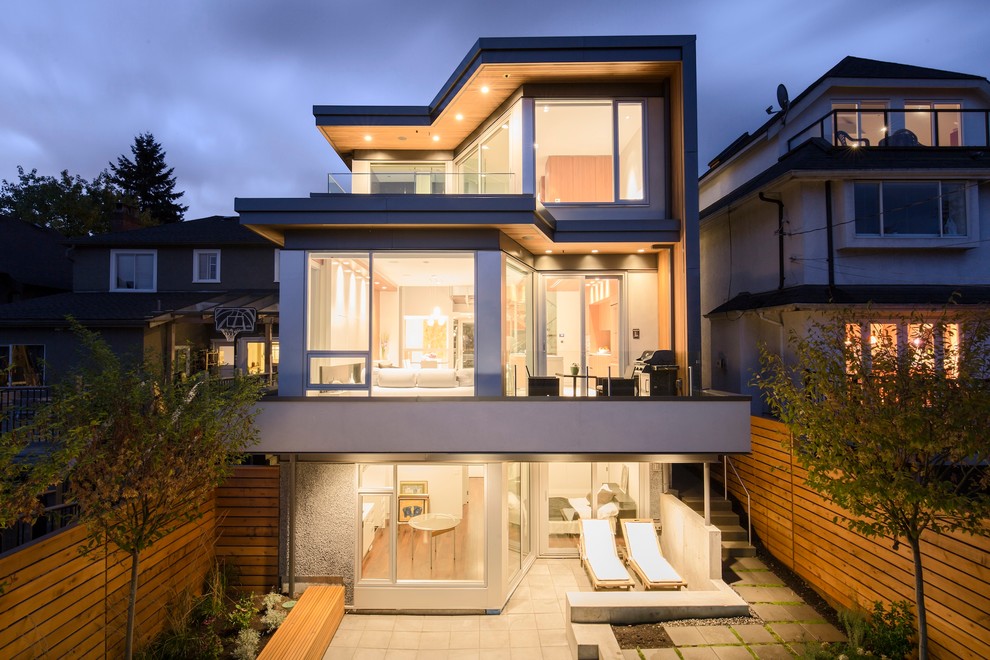 Photo of a mid-sized contemporary three-storey stucco grey exterior in Vancouver with a flat roof.