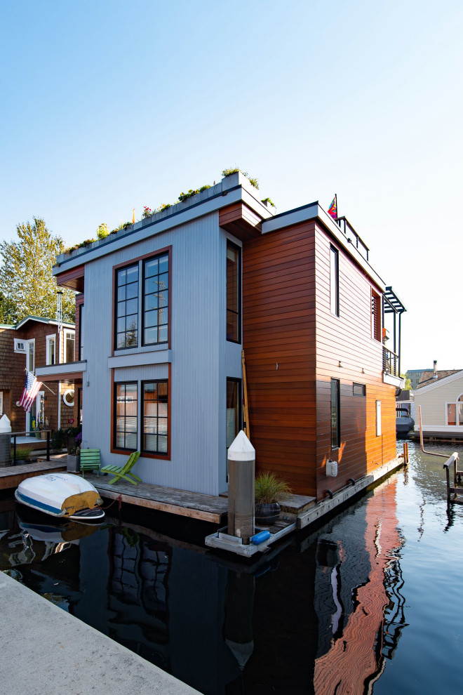 Aménagement d'une petite façade de maison bord de mer en bois à un étage avec un toit plat et un toit végétal.