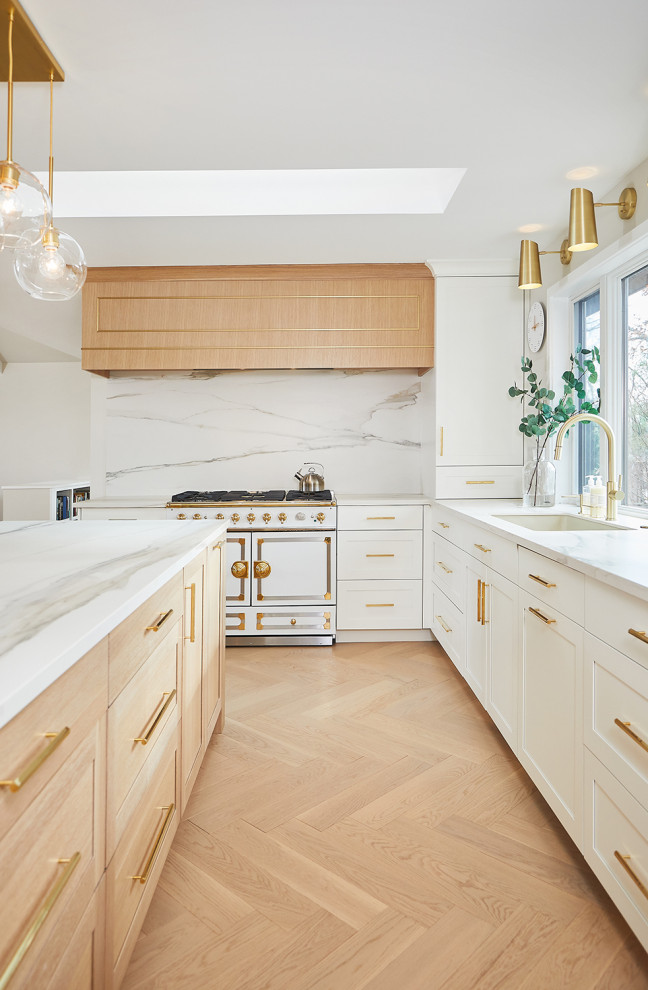 Design ideas for a large contemporary l-shaped eat-in kitchen in Grand Rapids with an undermount sink, shaker cabinets, light wood cabinets, white splashback, porcelain splashback, panelled appliances, light hardwood floors, with island and white benchtop.