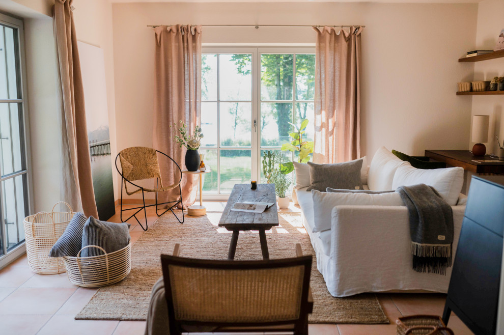 Ejemplo de sala de estar abierta mediterránea de tamaño medio con paredes beige, suelo de baldosas de terracota, chimenea de doble cara y suelo naranja