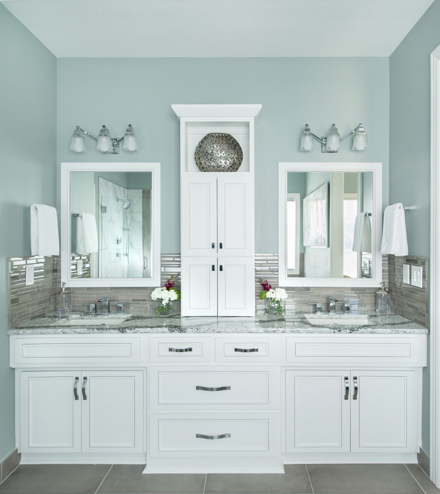 Photo of a mid-sized transitional master bathroom in Kansas City with raised-panel cabinets, white cabinets, a freestanding tub, an alcove shower, a two-piece toilet, gray tile, porcelain tile, blue walls, porcelain floors, an undermount sink, engineered quartz benchtops, grey floor, a hinged shower door and white benchtops.