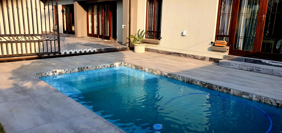 На фото: прямоугольный бассейн среднего размера на внутреннем дворе в средиземноморском стиле с фонтаном и покрытием из плитки с