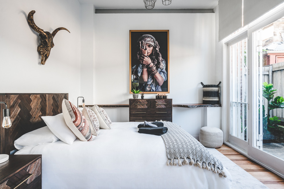 Inspiration for an eclectic master bedroom in Sydney with white walls, medium hardwood floors and brown floor.