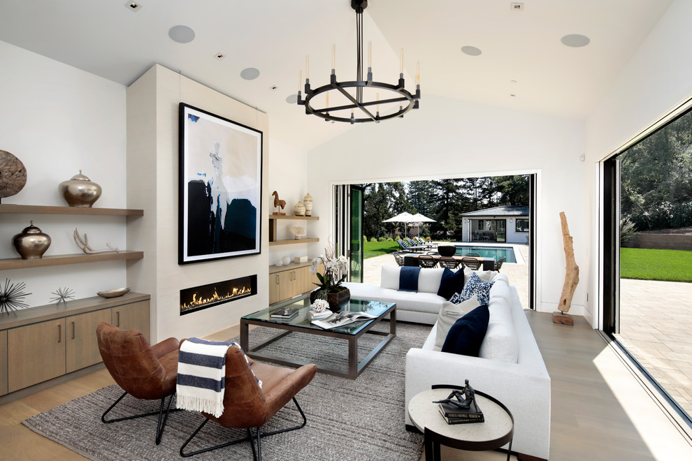 Photo of a transitional open concept family room in San Francisco with white walls, light hardwood floors, a ribbon fireplace and brown floor.