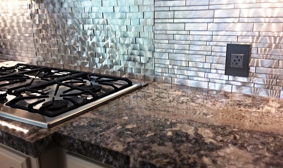 Example of a mid-sized transitional l-shaped travertine floor eat-in kitchen design in Houston with a farmhouse sink, raised-panel cabinets, white cabinets, granite countertops, metallic backsplash, metal backsplash, stainless steel appliances and an island