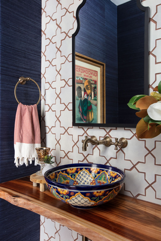 This is an example of a small mediterranean cloakroom in San Diego with white tiles, ceramic tiles, blue walls, terracotta flooring, a vessel sink, wooden worktops, brown floors, brown worktops, a floating vanity unit and wallpapered walls.