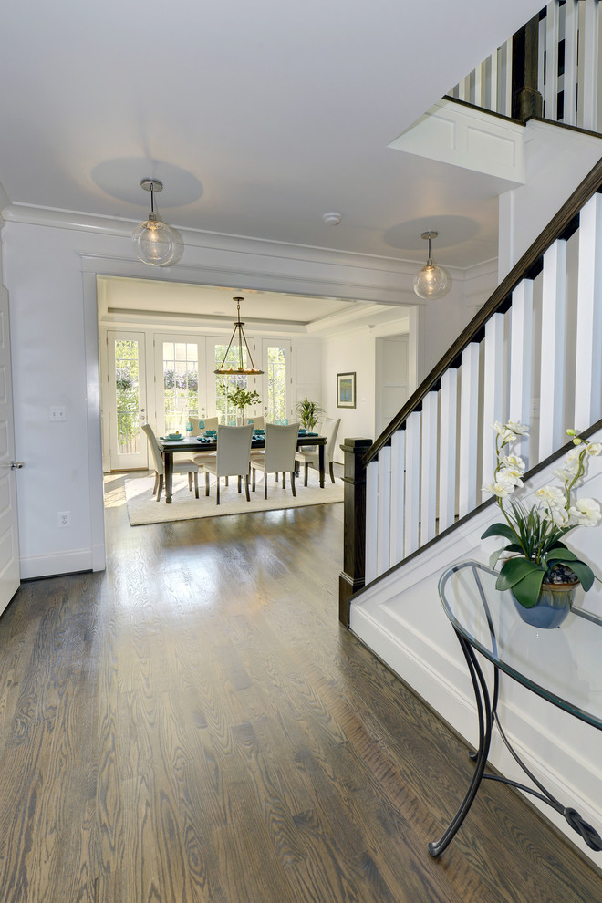 Example of a mid-sized transitional medium tone wood floor foyer design in DC Metro with white walls and a dark wood front door
