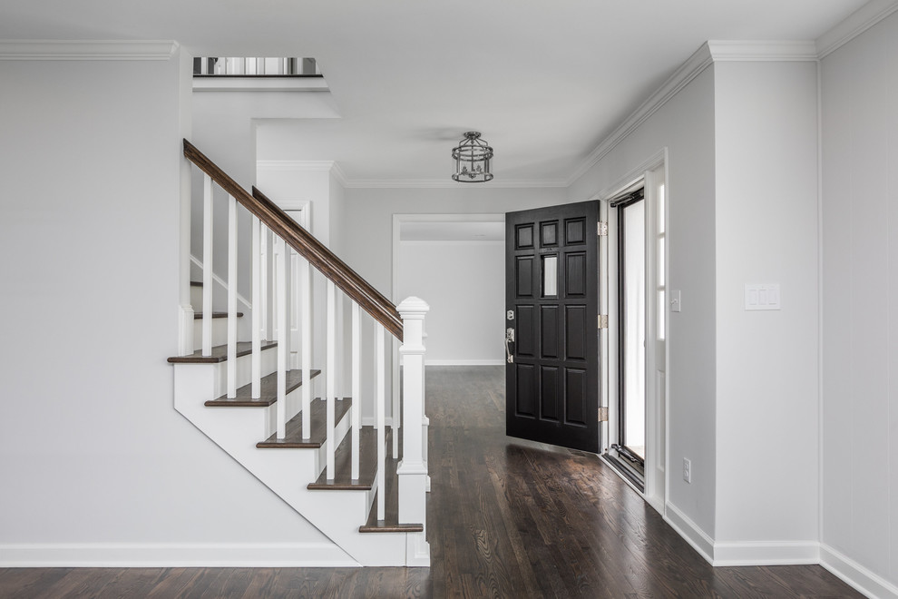 This is an example of a transitional foyer in Indianapolis with grey walls, dark hardwood floors, a single front door, a black front door and brown floor.
