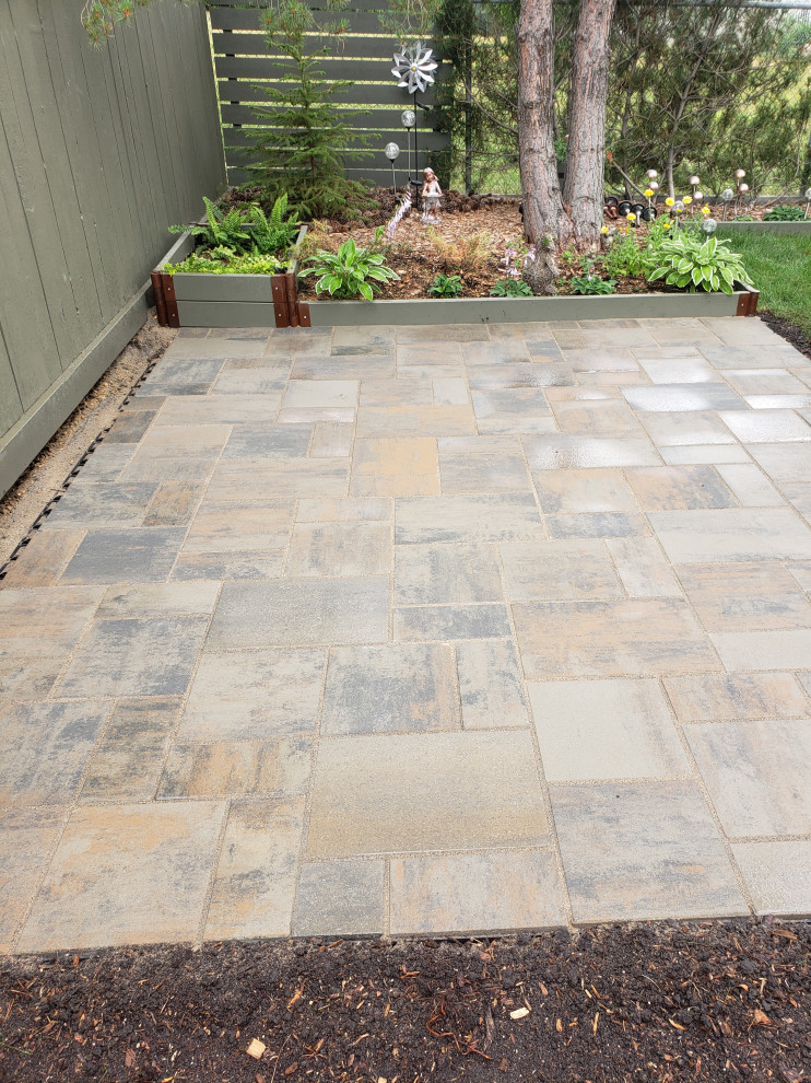 This is an example of a small rustic partial sun backyard concrete paver landscaping in Edmonton for summer.