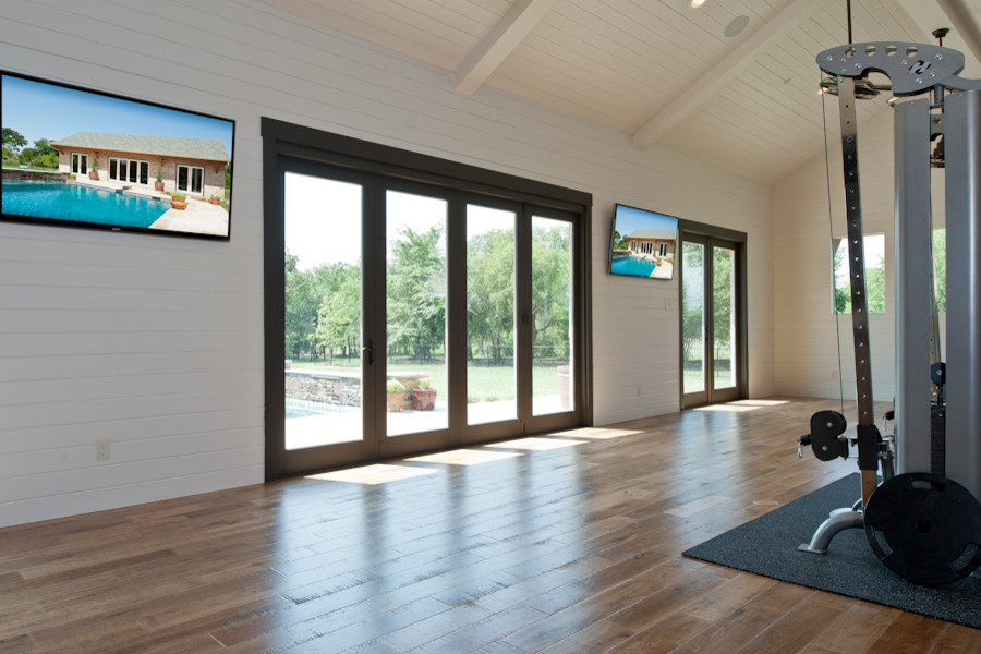 Large modern home weight room in Dallas with white walls and medium hardwood floors.