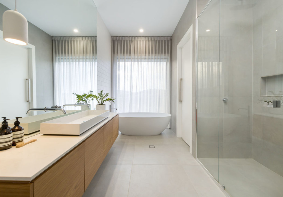 This is an example of a large contemporary master bathroom in Other with light wood cabinets, a freestanding tub, gray tile, porcelain tile, white walls, porcelain floors, engineered quartz benchtops, white floor and white benchtops.
