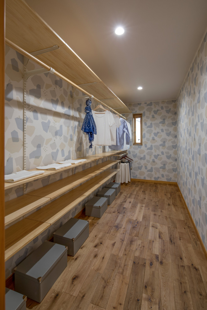 Ispirazione per una cabina armadio per donna scandinava di medie dimensioni con pavimento in legno massello medio, soffitto in carta da parati e pavimento marrone
