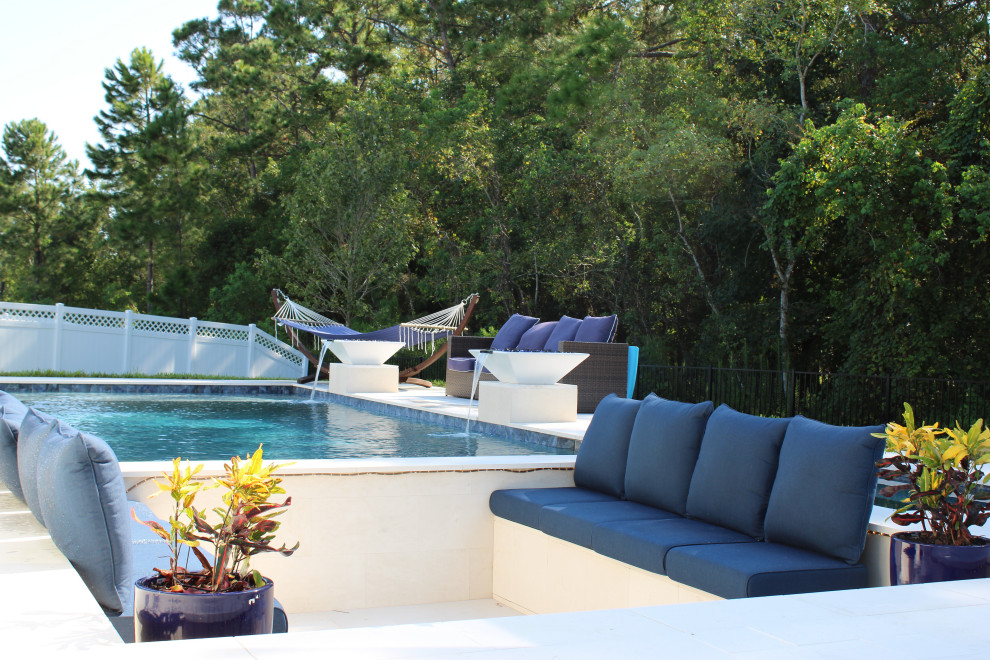 Mid-sized modern backyard custom-shaped pool in Jacksonville with a hot tub and natural stone pavers.