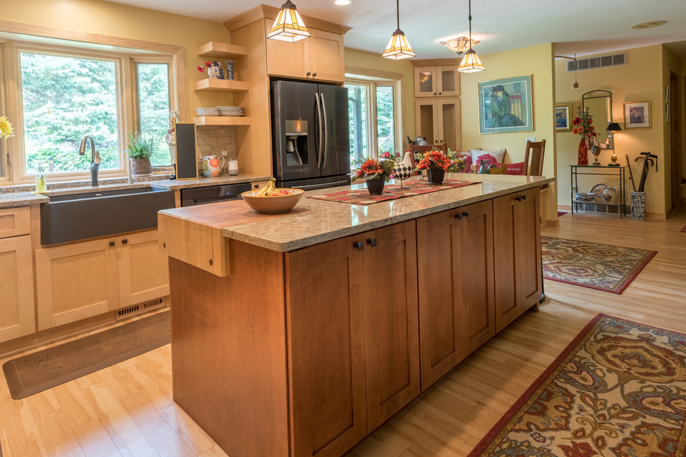 Large arts and crafts l-shaped eat-in kitchen in Minneapolis with a farmhouse sink, shaker cabinets, light wood cabinets, quartz benchtops, beige splashback, brick splashback, stainless steel appliances, light hardwood floors, with island, beige floor and beige benchtop.