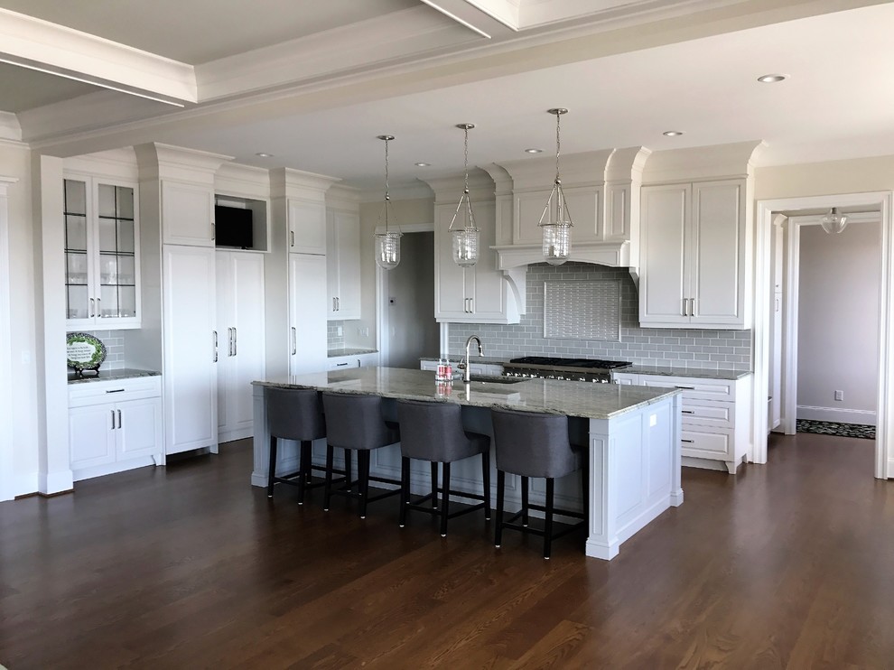 Eat-in kitchen - large traditional l-shaped dark wood floor eat-in kitchen idea with a single-bowl sink, raised-panel cabinets, white cabinets, quartz countertops, gray backsplash, porcelain backsplash, stainless steel appliances and an island