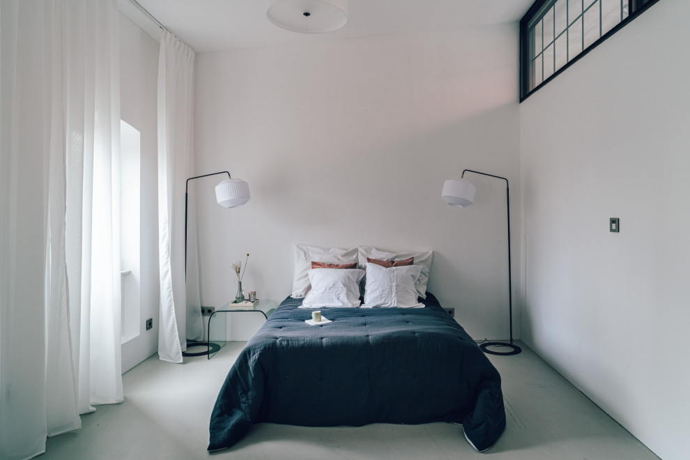 Imagen de habitación de invitados actual grande con paredes blancas, suelo de cemento y suelo gris