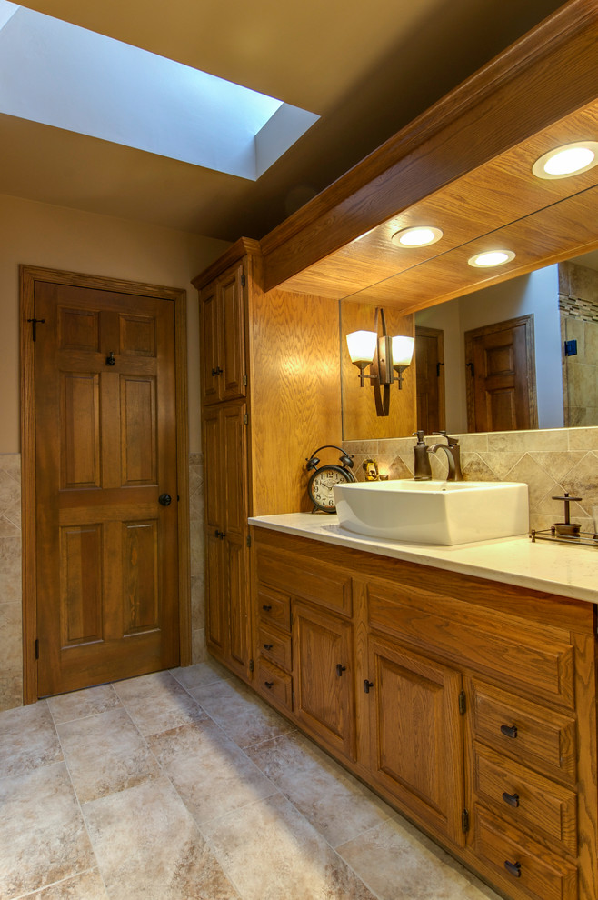 Inspiration for a large transitional master beige tile and ceramic tile ceramic tile and beige floor alcove shower remodel with raised-panel cabinets, medium tone wood cabinets, beige walls, a vessel sink, quartz countertops, a two-piece toilet and a hinged shower door