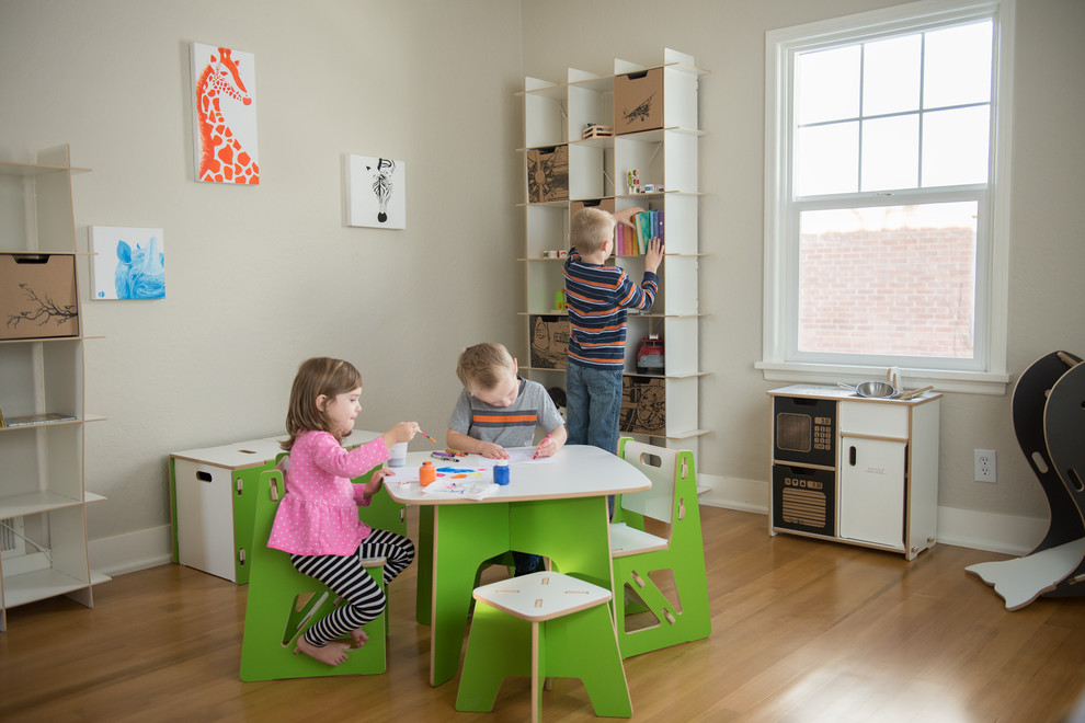 Mid-sized modern gender-neutral kids' playroom in Salt Lake City with white walls and light hardwood floors for kids 4-10 years old.