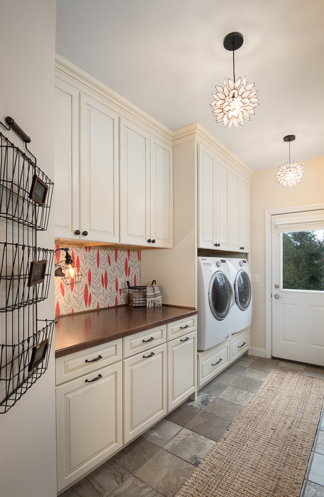 Inspiration for a country laundry room in Cincinnati with beige cabinets, beige walls, a side-by-side washer and dryer, wood benchtops, grey floor, brown benchtop and raised-panel cabinets.
