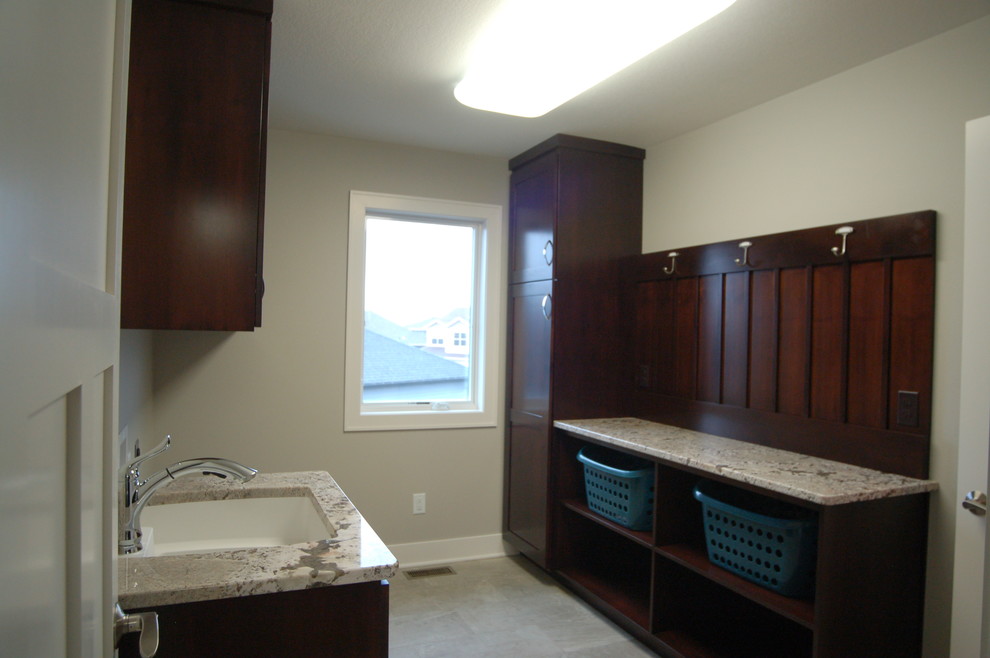Example of a small transitional galley porcelain tile dedicated laundry room design with an undermount sink, shaker cabinets, dark wood cabinets, granite countertops and gray walls