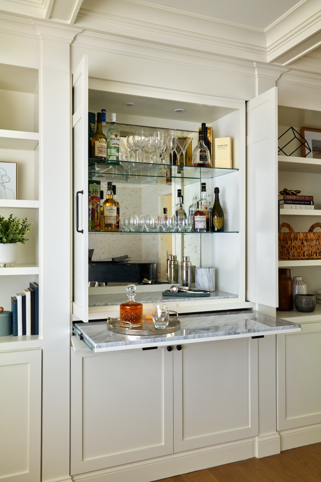 Modelo de salón con barra de bar abierto costero grande con paredes blancas, casetón y suelo de madera en tonos medios