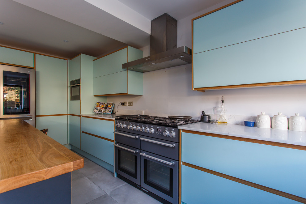 Inspiration for a medium sized midcentury l-shaped kitchen/diner in Sussex with a built-in sink, flat-panel cabinets, blue cabinets, quartz worktops, stainless steel appliances, an island and white worktops.
