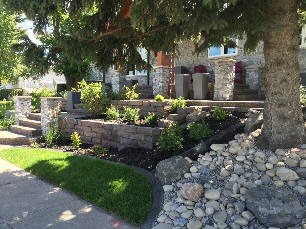 This is an example of a mid-sized front yard formal garden in Calgary with with raised garden bed and river rock.