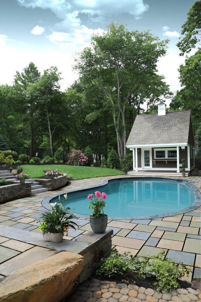 Mid-sized traditional backyard kidney-shaped pool in Boston with a pool house and natural stone pavers.