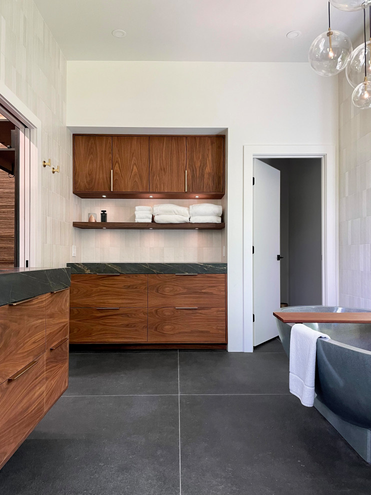 Photo of a large contemporary bathroom in New York with flat-panel cabinets, brown cabinets, a freestanding tub, an alcove shower, a bidet, beige tile, ceramic tile, white walls, porcelain floors, an undermount sink, soapstone benchtops, black floor, an open shower, black benchtops, a shower seat, a double vanity, a floating vanity, vaulted and wood walls.