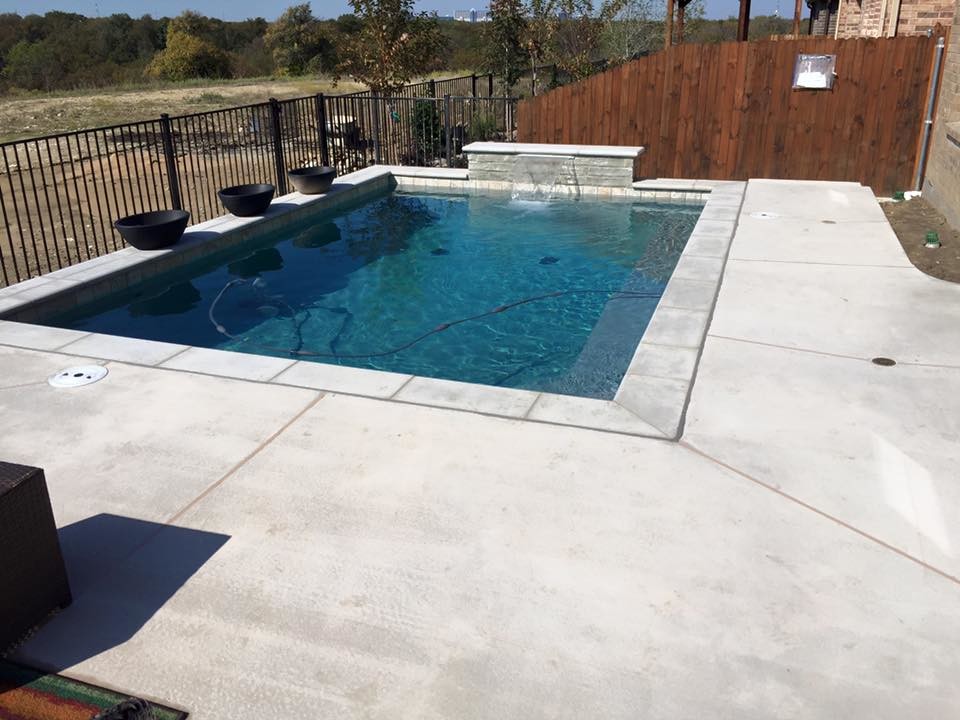 Design ideas for a small contemporary backyard rectangular lap pool in Dallas with a water feature and concrete slab.