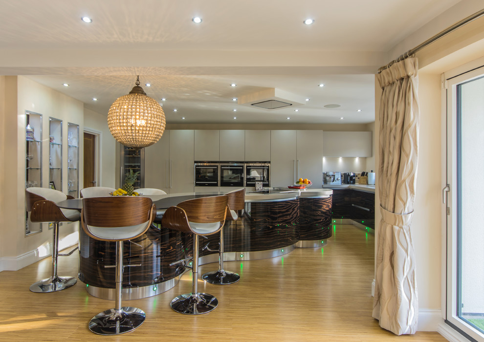 Photo of a modern open plan kitchen in Cheshire with flat-panel cabinets, white cabinets, white appliances, laminate floors and an island.