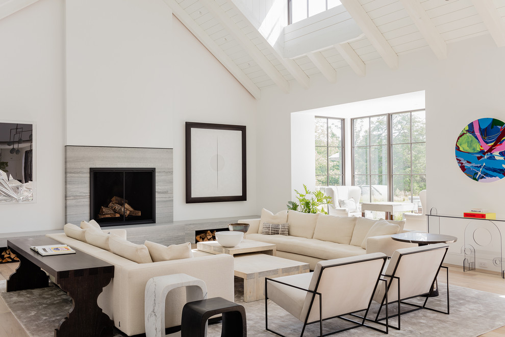 Contemporary open concept living room in Boston with white walls, light hardwood floors, a standard fireplace, a stone fireplace surround and beige floor.