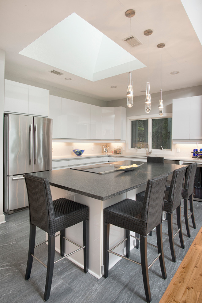 Mid-sized transitional u-shaped open plan kitchen in Charleston with an undermount sink, flat-panel cabinets, white cabinets, soapstone benchtops, marble splashback, stainless steel appliances, slate floors, with island, grey floor and grey benchtop.